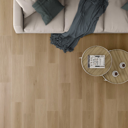 Un sofá beige con cojines verde azulado se encuentra junto a una mesa de café de madera sobre un piso de madera clara, creando u