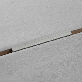 Eine hellgraue Betonfliese bildet eine fugenlose Oberfläche mit einem schmalen, eingelassenen, horizontal verlaufenden Aluminium