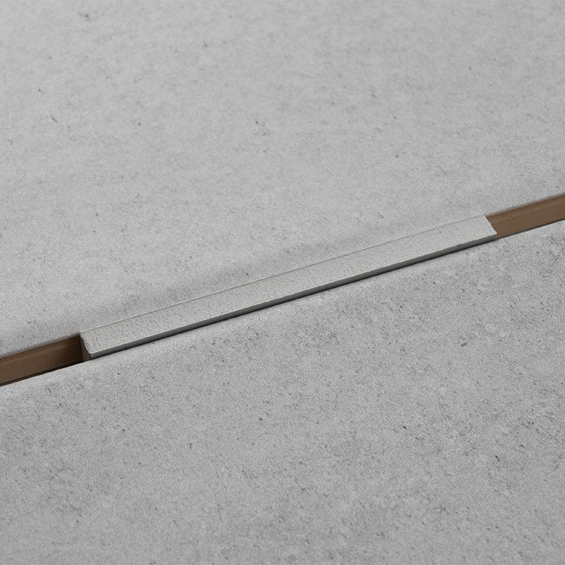 Una losa de hormigón de color gris claro forma una superficie sin costuras con una tira de aluminio estrecha y empotrada que se 