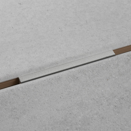 Eine hellgraue Betonfliese bildet eine fugenlose Oberfläche mit einem schmalen, eingelassenen, horizontal verlaufenden Aluminium Eine hellgraue Betonfliese bildet eine fugenlose Oberfläche mit einem schmalen, eingelassenen, horizontal verlaufenden Aluminium