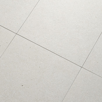 Les carreaux de pierre grise sont alignés selon un motif en grille, formant une surface de sol lisse et uniforme. De fines ligne