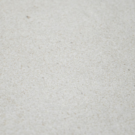 Die Fliese hat eine hellbeige Struktur, liegt flach auf der Oberfläche und zeigt bei natürlichem Licht subtile Sprenkel.