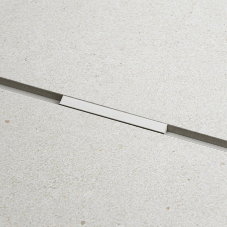 Een gladde, lichtbeige rechthoekige tegel met een subtiele textuur en een dunne, horizontale metalen strip in het midden, wat vo Een gladde, lichtbeige rechthoekige tegel met een subtiele textuur en een dunne, horizontale metalen strip in het midden, wat vo