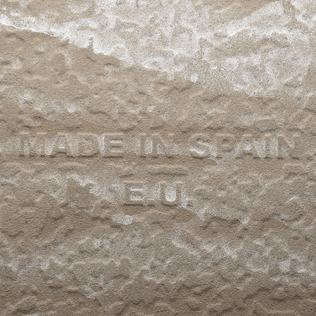 Azulejo bege de textura áspera, com os textos `MADE IN SPAIN` e `E.U.` em relevo, sugerindo sua origem, exibido em close-up.