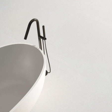 Uma elegante banheira branca fica em um piso liso e amplo em cinza claro, acompanhada por uma moderna torneira preta, criando um