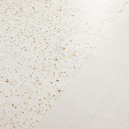 Tiles transition from terrazzo, speckled with multicolored chips, to plain white, creating a pattern on the smooth floor surface