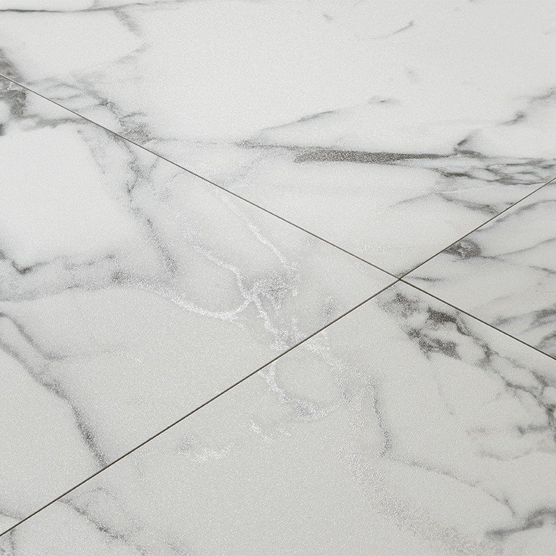 Azulejo cerámico blanco con vetas grises; juntas forman una X sobre superficie pulida y brillante, evocando mármol, con patrón irregular de vetas oscuras y zonas satinadas.