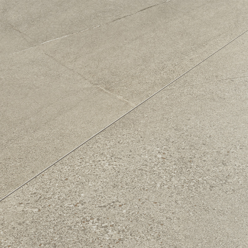Fliese mit beigegrauem, leicht körnigem Betonfinish, sichtbaren Fugenlinien und feinen Rissspuren, matte Oberfläche, wahrscheinlich als Boden- oder Wandbelag verwendet.