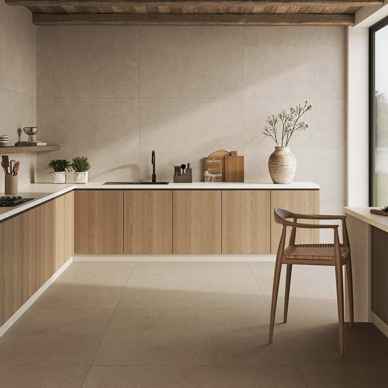 Große beige Bodenfliese in moderner, minimalistischer Küche; helle Wandfliesen, Holzunterschränke, weiße Arbeitsplatte mit Spüle, offenes Fenster, Stuhl, Vase und Küchenutensilien.