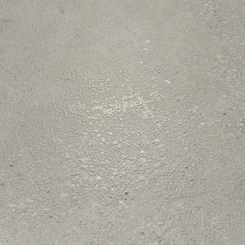 Helle beige‑graue Fliese mit rauer, körniger Oberfläche und vereinzelten hellen Ablagerungen; liegt flach als ebener Bodenbelag ohne erkennbare Fugen oder Gegenstände.