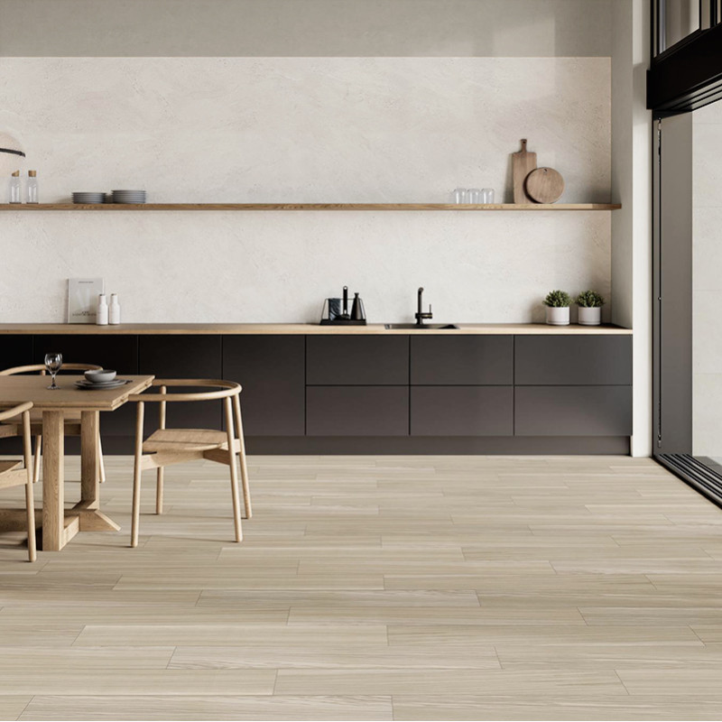 Azulejo: suelo de tablones cerámicos efecto madera claro; contexto: cocina minimalista con encimera y estantería de madera, armarios bajos oscuros, mesa con sillas y ventanal lateral.