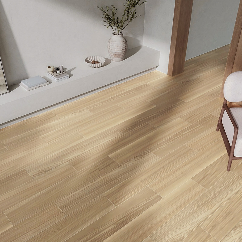 Suelo de baldosa imitación madera, tablones claros y vetas suaves; alrededor, mueble bajo empotrado con jarrón y objetos decorativos, pared neutra y una silla tapizada.