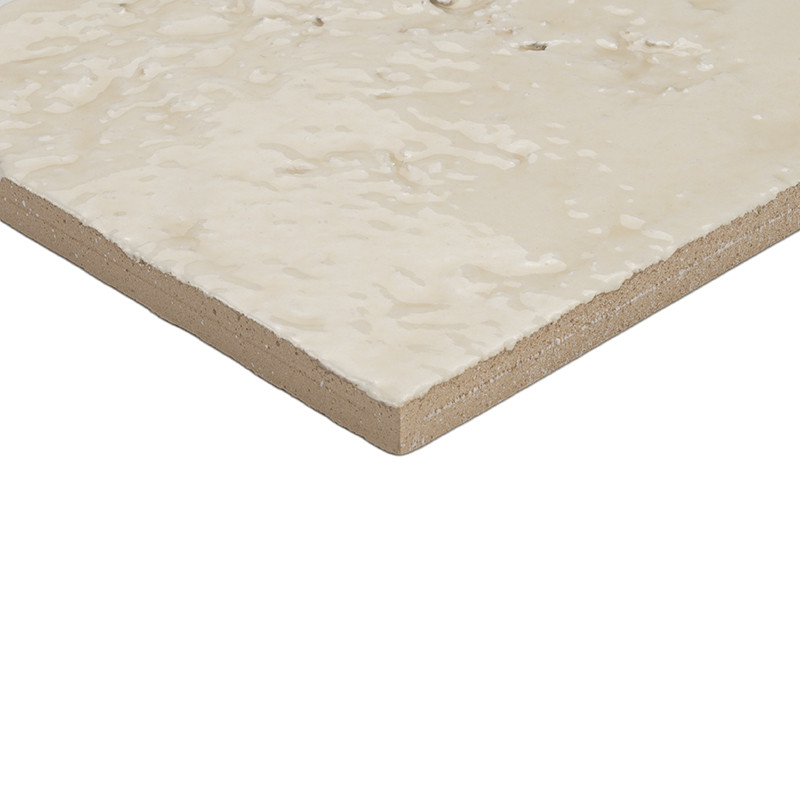 Fliese: Eckansicht, beige‑creme glasierte, leicht strukturierte Oberfläche; braun‑beige Kante sichtbar; freigestellt vor weißem Hintergrund.