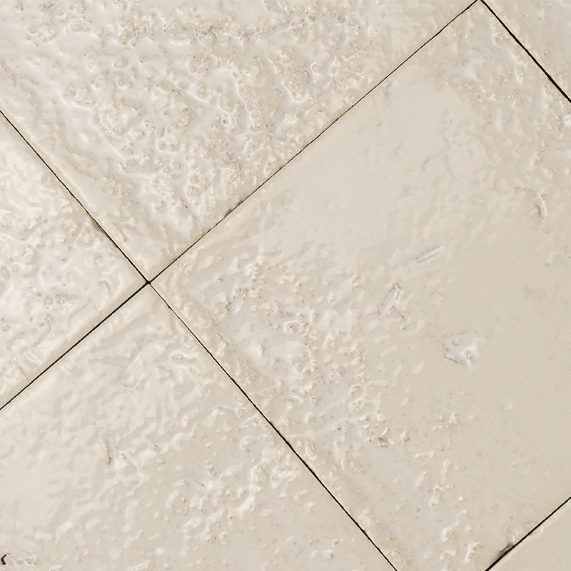 Quadratische beige Keramikfliesen mit unregelmäßig strukturierter, matt-rauer Oberfläche; diagonale Anordnung, feine dunkle Fugen trennen die Fliesen.
