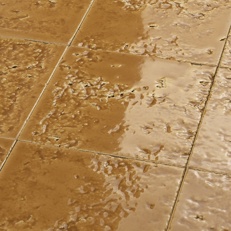 Glossy rectangular ceramic tile with an irregular surface and puddles; visible joints between pieces forming a wet floor, worn appearance and possibly outdoors or in a lobby.