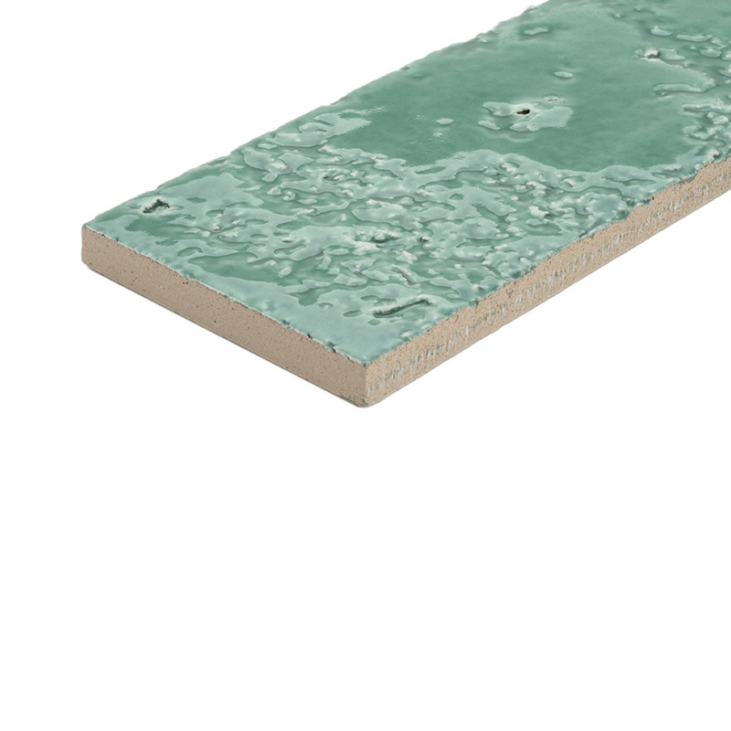 Rectangular tile glazed in aqua green, textured and glossy surface; visible beige ceramic edge and core; placed at an angle on a neutral white background.