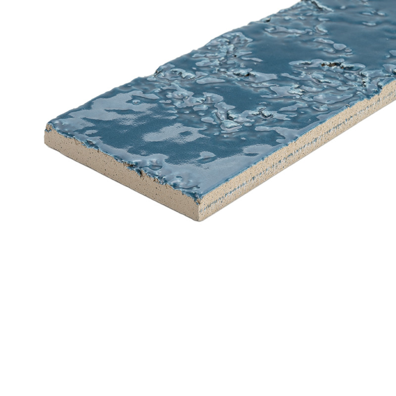 Carrelage rectangulaire bleu émaillé à surface texturée brillante, bord brut en céramique apparent, présenté sur fond blanc isolé.