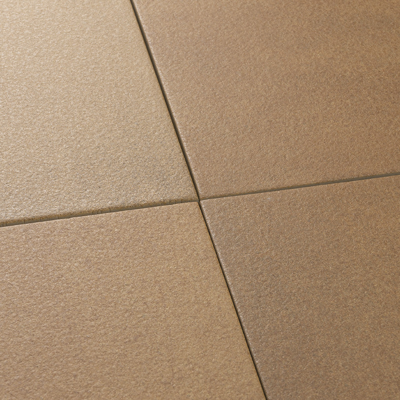 Carrelage brun clair: quatre carreaux se rejoignent en croix, joints fins gris, surface mate légèrement granuleuse, plan rapproché.