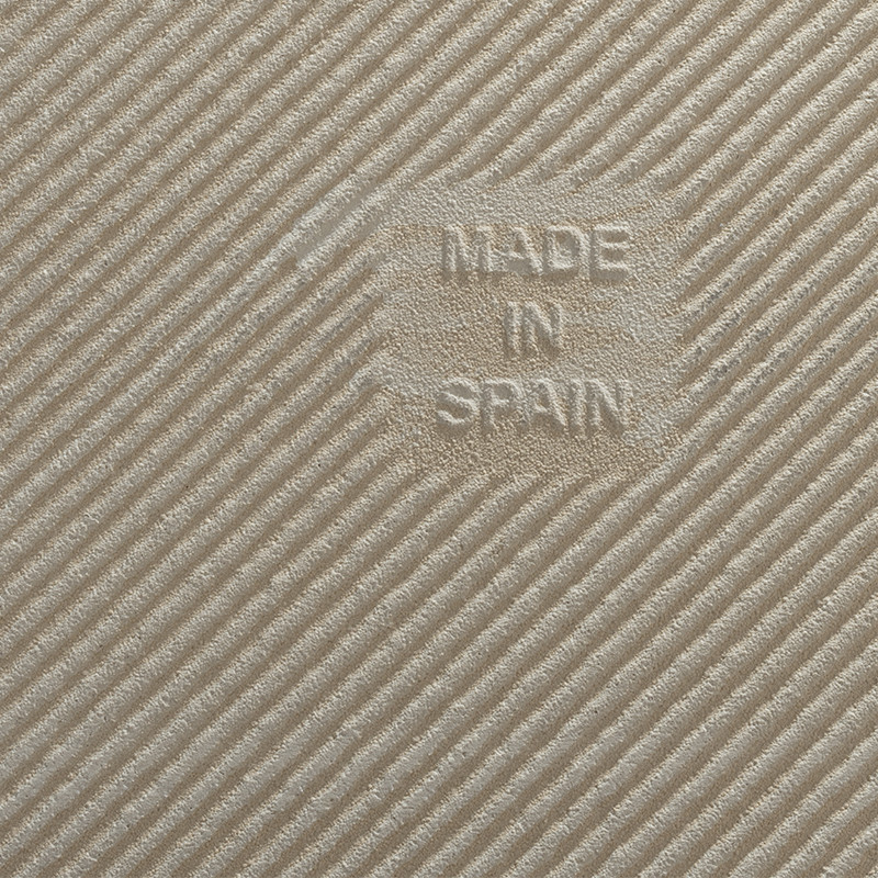 Beige, diagonalgemusterte Fliese (Nahaufnahme) mit feiner gerippter Textur; zentrales, leicht erhabenes Quadrat mit Prägung "MADE IN SPAIN".