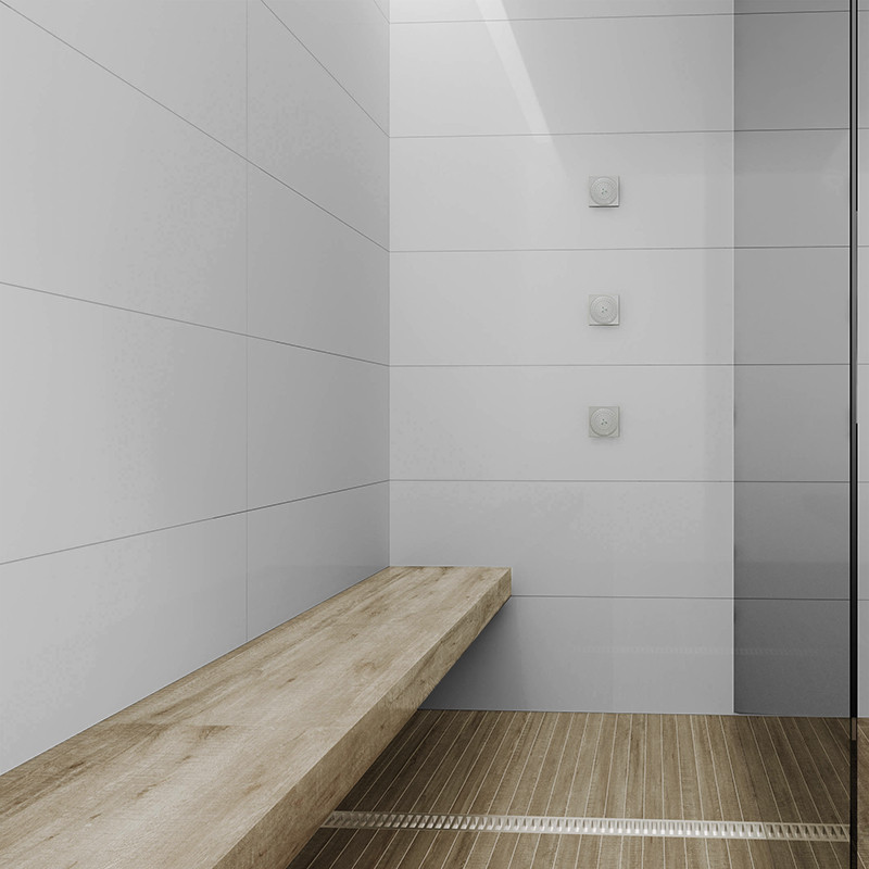 Plain white tile on shower wall; long built-in wooden bench and wooden slat flooring with drainage channel; glass screen on the right.