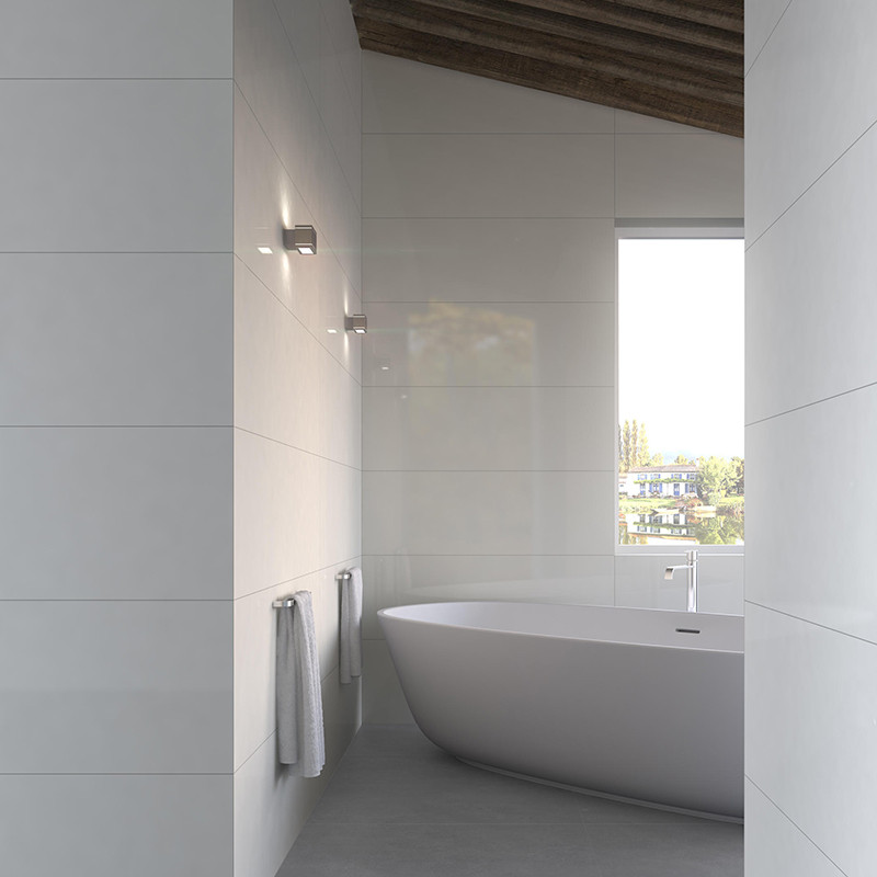 Glanzende witte wandtegel: moderne badkamer met vrijstaand ovaal bad, twee handdoeken aan rek, wandlampen, schuine houten plafondbalken en raam met buitenzicht.