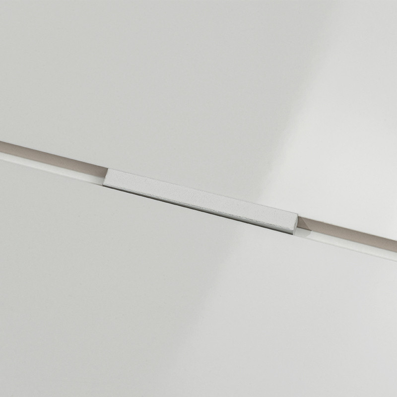 Witte glanzende tegel met smalle zilverkleurige voegstrip in de naad tussen twee tegels, close-up van vlakke, lichtreflecterende oppervlakken.