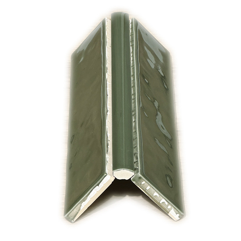 Carrelage d'angle en céramique vert olive vernissé, profilé en V à deux ailes, chants blancs apparents, présenté isolé sur fond blanc.