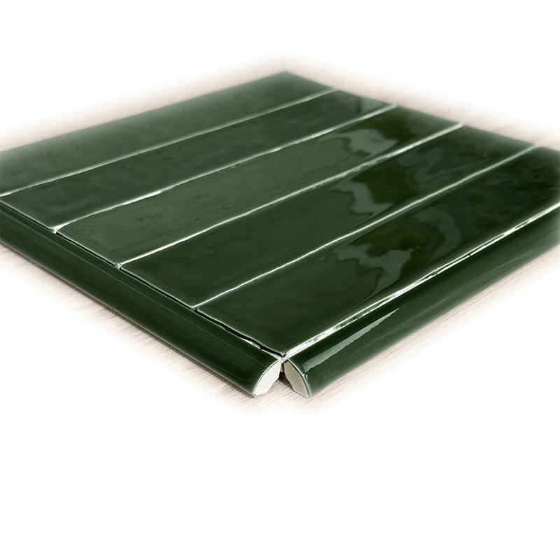 Azulejo retangular verde escuro brilhante disposto em fileiras longitudinais; borda chanfrada, superfície vidrada com reflexos, apoiado sobre fundo branco.