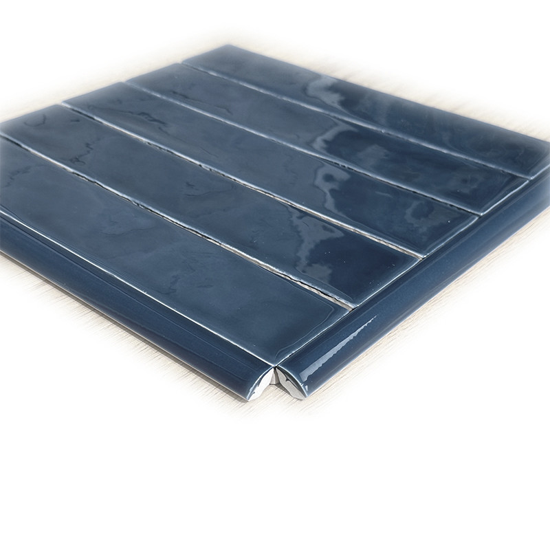Bright blue ceramic tile, rectangular format with five horizontal stripes in relief and beveled edge; placed on a neutral white surface.