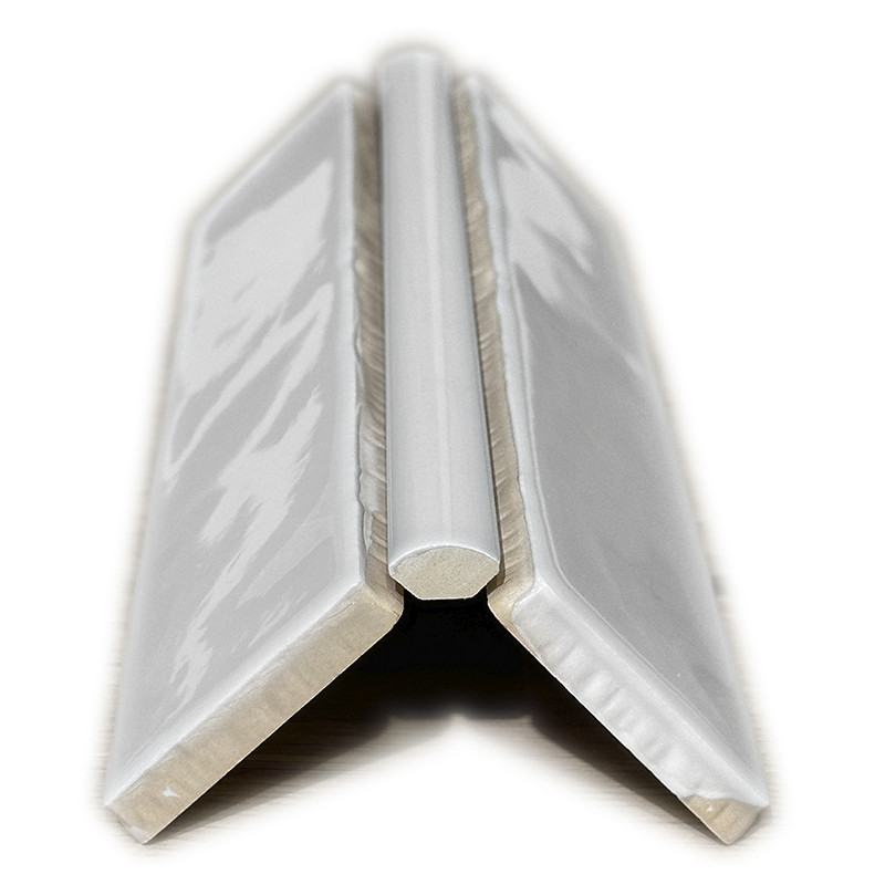 White glazed 'V' angular tile with beveled profile and central insert, photographed on a white background with shadow underneath.