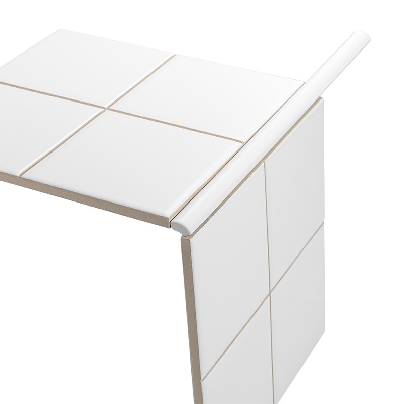 Azulejo branco em L com seis pastilhas lisas e rejunte bege; borda arredondada com perfil de acabamento prateado, apresentado isolado sobre fundo branco em perspectiva.