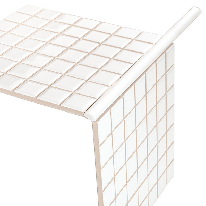 Carrelage blanc à carreaux carrés avec joints beige, formant un angle en L entre une surface horizontale et une verticale, bord arrondi en saillie.