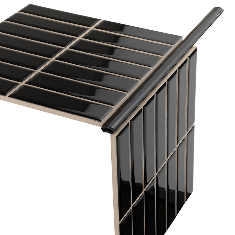 Black, rectangular, glossy glazed tiles arranged in perpendicular panels with beige joints and edges, forming a corner; neutral white background.