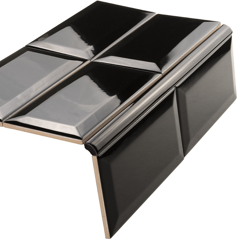 Carrelage céramique noir brillant, rectangles chanfreinés en relief formant un élément d'angle (profil de bordure), présenté isolé sur fond blanc.