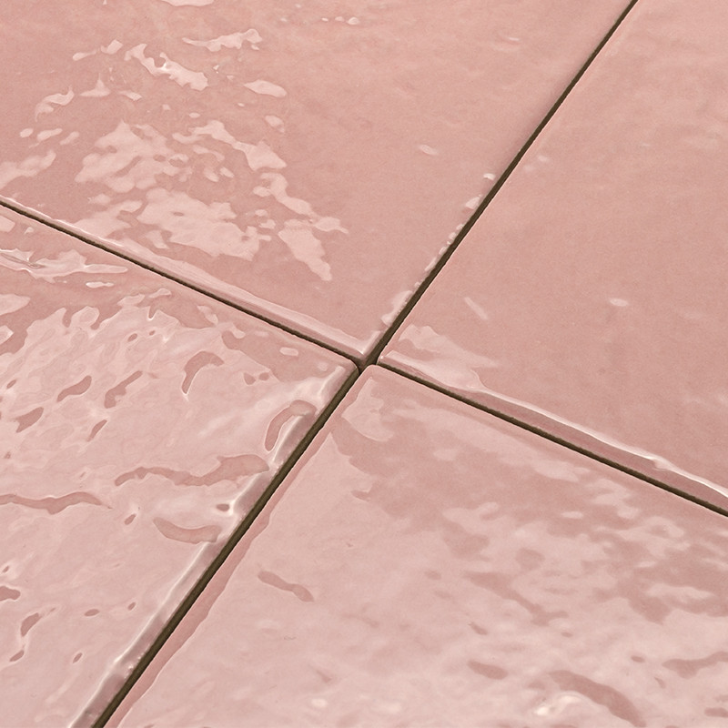 Carrelage rose saumon brillant: quatre carreaux en croix, joints fins, surface mouillée avec reflets.