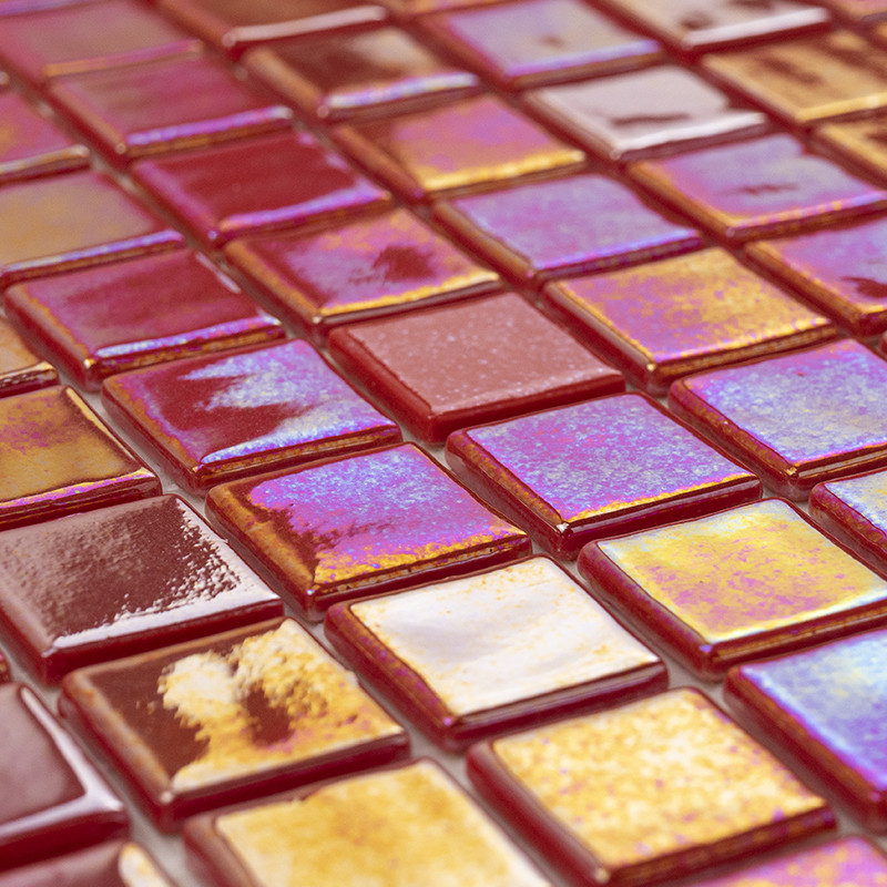 Azulejos cuadrados vidriados iridiscentes en tonos rojos, púrpura y dorado; dispuestos en cuadrícula apilada, con reflejos brillantes y textura vidriada.