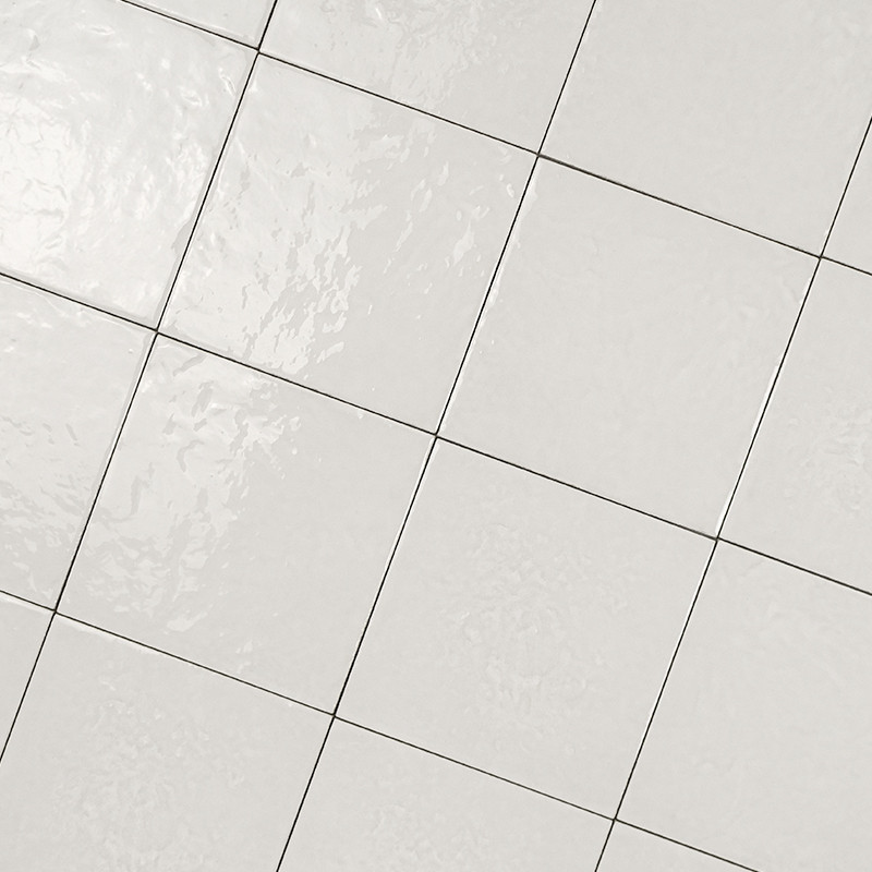 Carrelage blanc brillant à joints fins formant une grille inclinée, apparence lisse et légèrement réfléchissante, plan rapproché centré sur les carreaux sans éléments environnants visibles.