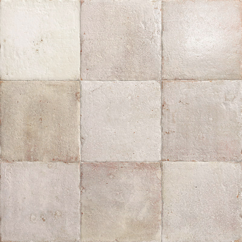 Carrelage 3x3 de carreaux carrés en céramique patinée posés au sol, tons crème et beige, joints fins, surface légèrement usée et taches discrètes.
