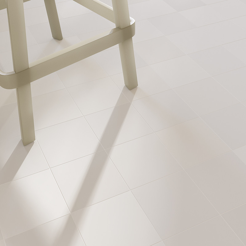 Carrelage carré blanc crème, finition brillante et joints fins; pied de tabouret beige posé dessus, ombre allongée projetée sur le sol.