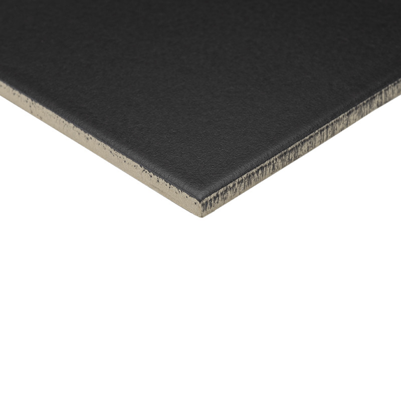 Matte black rectangular tile; exposed edge reveals beige core, shown in perspective and isolated on white background.