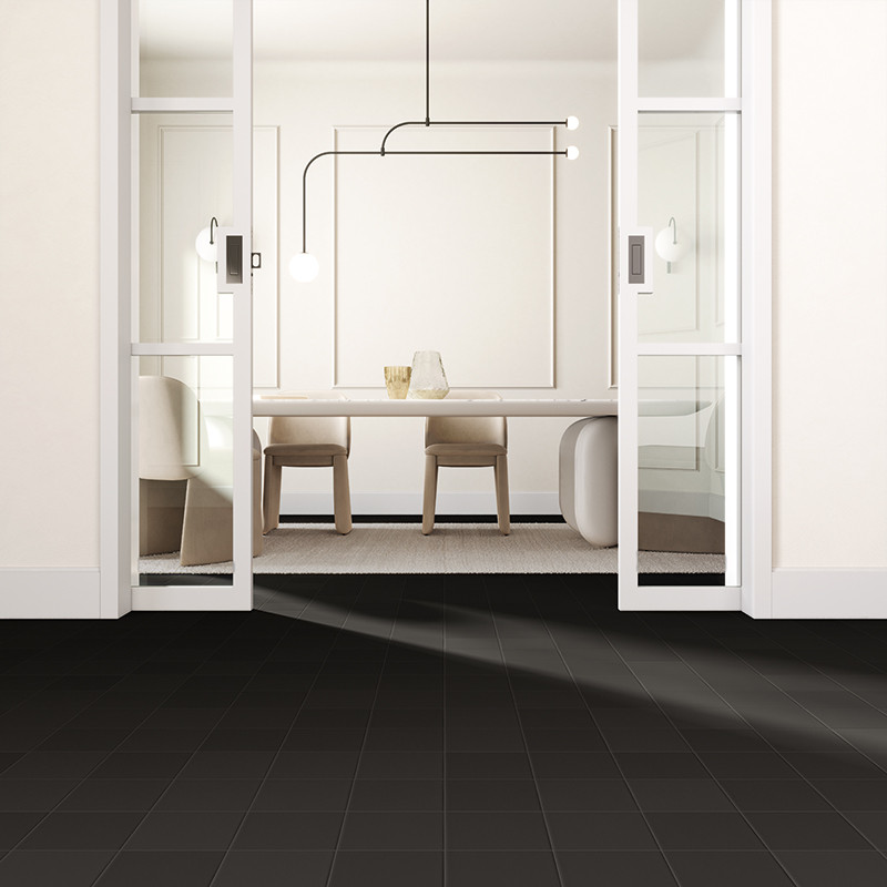 Dunkle quadratische Bodenfliesen im Vordergrund; im Hintergrund helle, minimalistische Essnische mit Glastüren, Tisch, zwei Stühlen und filigraner Pendelleuchte.