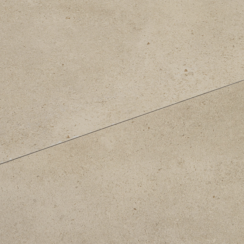 Azulejo beige claro con textura mate y pequeñas motas, separado por una junta diagonal fina; apariencia de pavimento o revestimiento cerámico uniforme.