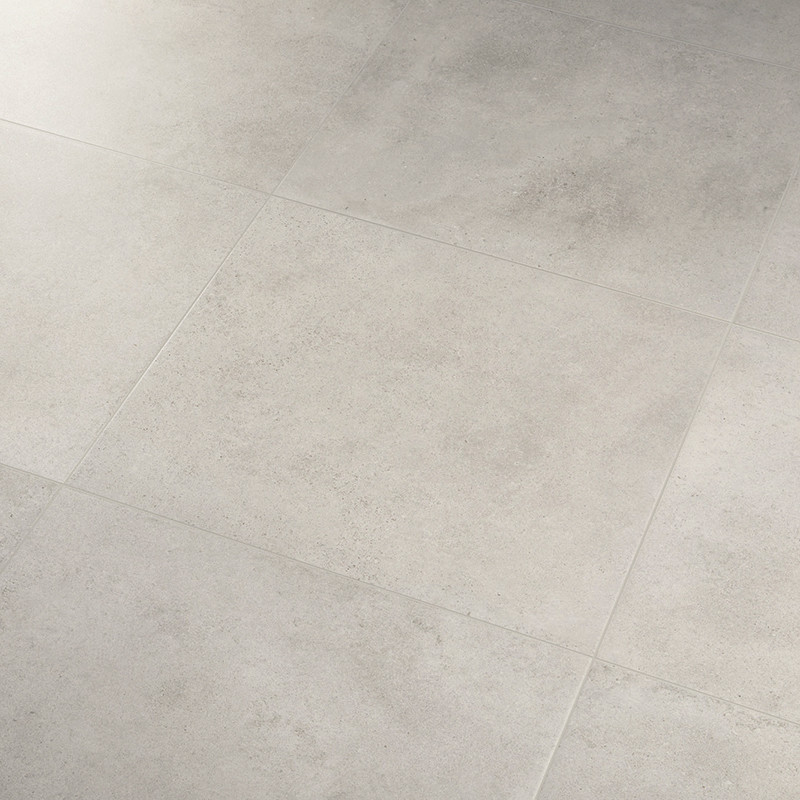 Carrelage grand format gris clair, carreaux carrés aux joints fins; sol mat légèrement texturé, éclairage doux créant ombres et variations tonales.