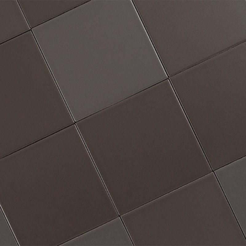 Carrelage de carreaux carrés gris anthracite à surface mate, joints fins, agencement en légère perspective suggérant un sol intérieur uniforme.