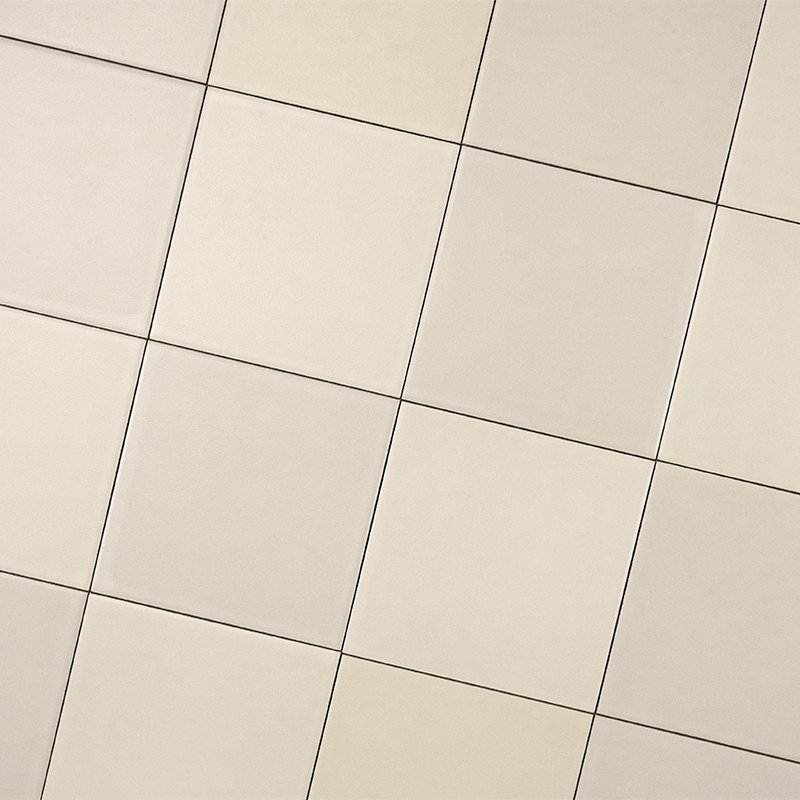 Azulejos cuadrados beige claro, superficie lisa; dispuestos en una cuadrícula rotada en diagonal, separados por juntas finas y líneas oscuras, ocupando todo el encuadre.