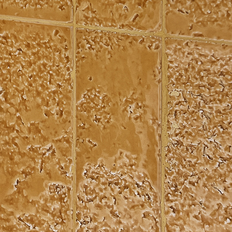 Textured beige ceramic tile with irregular reliefs; thin cream-colored joints forming a grid, surrounded by similar tiles.