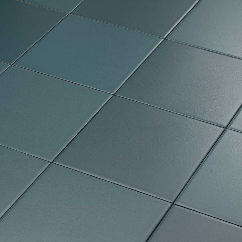 Azulejos cerámicos azul verdoso, superficie lisa y ligeramente reflectante; dispuestos en cuadrícula con juntas finas, formando un suelo o revestimiento plano bajo luz suave.