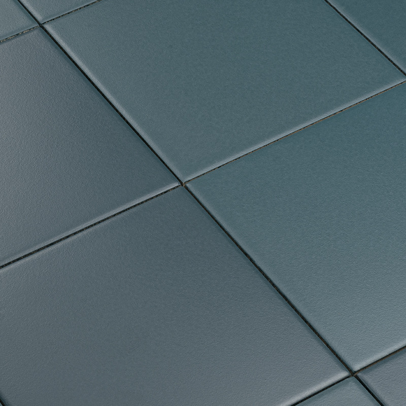 Tegel: vierkante, matte, blauwgroene tegels met fijne korrel en gefreesde randen; Context: close-up diagonale lay-out met smalle, lichtgrijze voeglijnen.