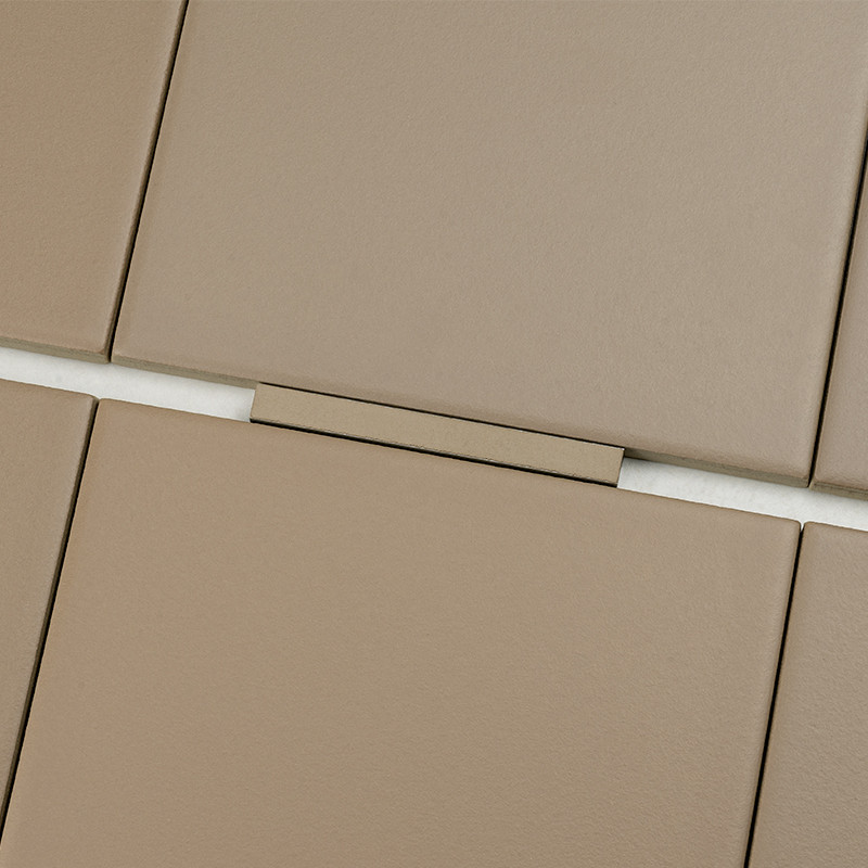 Carrelage beige mat — carreaux rectangulaires séparés par joints blancs étroits et une entretoise rectangulaire centrale; gros plan montrant surfaces lisses et éclairage neutre.