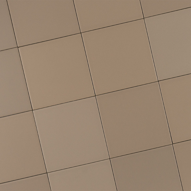 Carrelage beige composé de grands carreaux carrés disposés en grille, joints fins et ombrages légers suggérant surface légèrement courbée ou perspective.